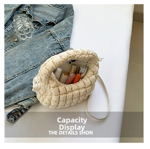 Detail showing internal capacity of the beige puffy bag with phone and lipsticks