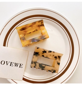 Detail of square cutout acetic acid hair claws in amber and cream shell patterns