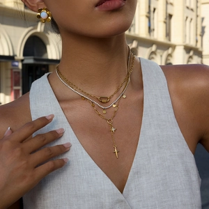 Colliers multicouches dorés avec pendentifs étoile et croix portés par un mannequin