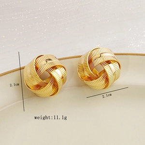 Detailed macro view of gold geometric woven earrings with intricate ribbed metal texture