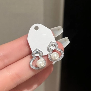 Detail of silver gourd earrings set with shimmering zircons and elegant central pearls