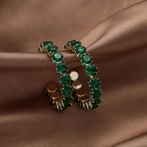 Vintage geometric gold hoop earrings with emerald green crystals on brown silk background