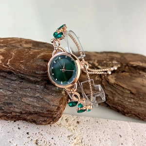 Detail of rose gold bracelet watch with green dial and leaf-shaped gemstones