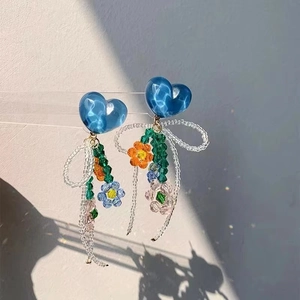 Detailed shot of long tassel earrings with blue heart and colorful beaded butterfly motifs