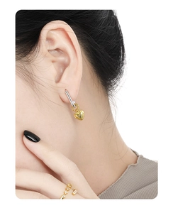 Detailed view of bicolor S925 sterling silver heart earrings worn by a model
