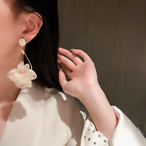 Elegant fabric flower drop earrings with white beads and metal frame worn by a model