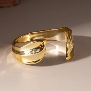Close-up of golden irregular wavy texture on wide open bangle with mirror finish