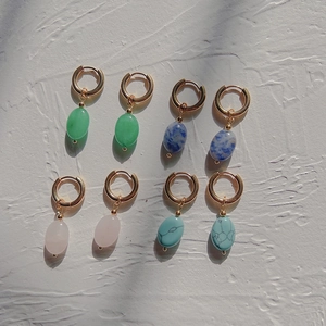 Flat lay of four gold hoop earrings with green, blue, pink, and turquoise natural stones