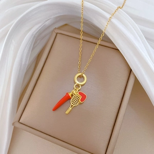 Detail of luxury gold necklace with red heart and pepper pendants in a jewelry box