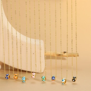 Golden necklace with eight colorful enamel evil eye charms on a rustic stone background