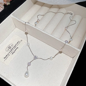 Detail of Y-shaped pearl necklace with zircon flower and teardrop pearl on velvet
