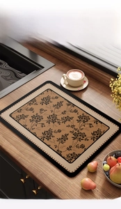 Absorbent kitchen drying mat with brown floral pattern and grid border on wooden surface
