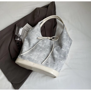 Detailed top view of a grey canvas bucket bag with white bow print and leather trim