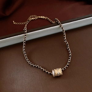 Detail of vintage gold chain with black leather and floral cylinder pendant necklace