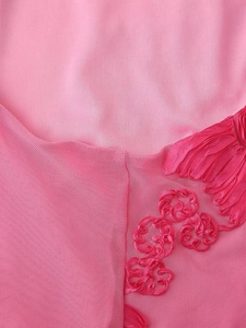 Gros plan d'une robe en résille rose avec broderie florale détaillée et couture fine