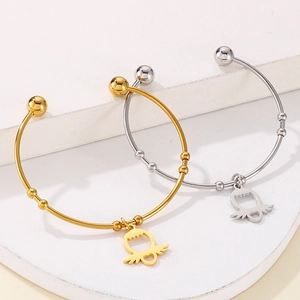 Minimalist open steel bangles with heart wing charms in gold and silver finishes