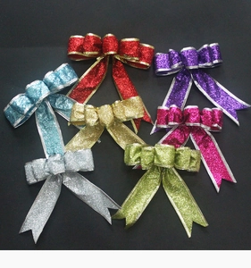 Close-up of colorful glitter Christmas bows in red, gold, blue and silver on dark background