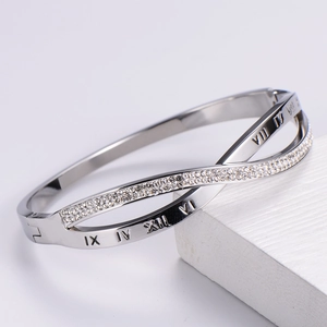 Macro detail of silver crossover bangle with Roman numerals and pavé crystals