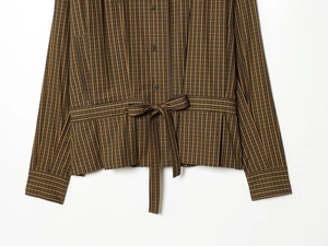 Close-up of brown plaid shirt featuring waist tie-knot and textured woven fabric