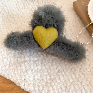 Detail view of plush grey heart hair claw clip with faux fur texture on soft fabric