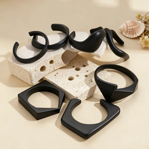 Detailed close-up of matte black acrylic geometric rings on minimalist stone display