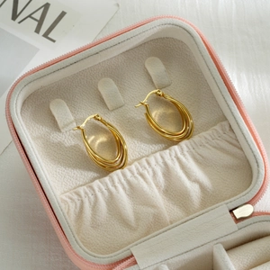 Golden multi-layer U-shaped stainless steel earrings displayed in a pink jewelry case