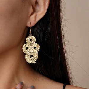 Detail of gold geometric earrings featuring four textured spiral discs on a female model