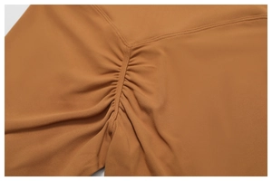 Macro detail of high-waist yoga pants with scrunch butt seam in caramel brown color