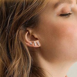 Detailed view of sterling silver star and bar stud earrings set on ear model