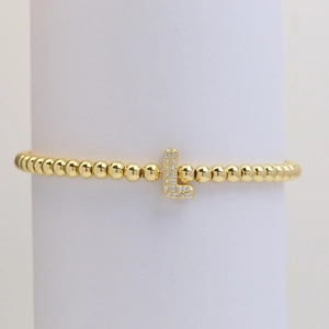 Close-up of gold beaded bracelet with a micro-paved cubic zirconia letter L charm