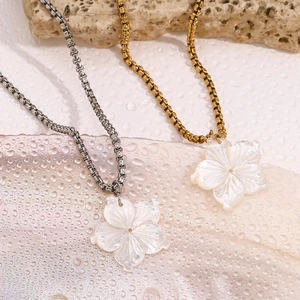 Nahaufnahme doppellagiger Ketten in Gold und Silber mit Anhängern in Perlmuttblumenform