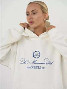 Detail of cream oversized hoodie with The Movement Club lettering and dropped shoulder
