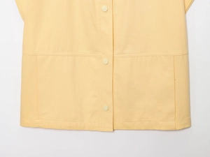 Détail de gilet jaune montrant des poches symétriques et des boutons assortis en sergé