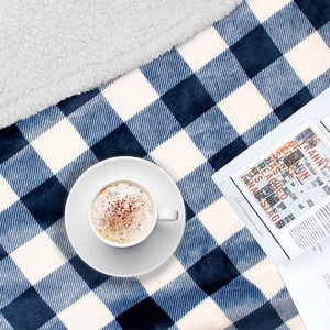 Detailed texture of blue and white plaid flannel blanket with coffee and magazine setup