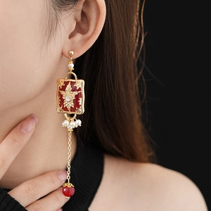 Close-up of vintage flower earrings with red enamel charms and pearl tassels on model