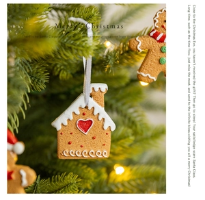 Gingerbread house and man hanging ornaments on a Christmas tree with festive warm lights