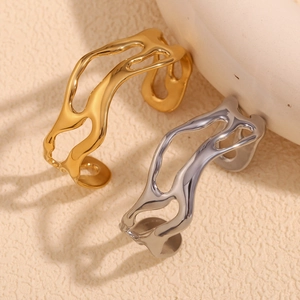 Detail of minimalist wave hollow bangles in gold and silver finish on beige background