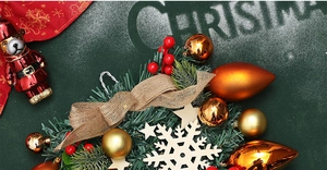 Close-up of Christmas pine wreath with burlap bow, red berries and golden balls