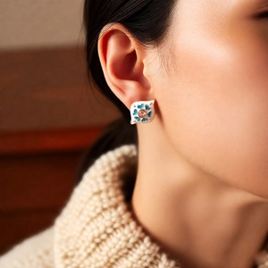 Macro shot of vintage enamel diamond earrings with pink gemstone and blue floral patterns