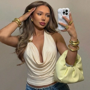 Détail du haut dos nu plissé beige à texture soyeuse avec des bijoux dorés