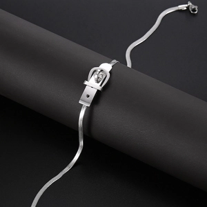 Close-up of a silver buckle-style belt necklace with flat snake chain on a black stand