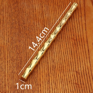 Detailed view of bamboo-shaped brass pen on a dark wood surface with elegant engraving