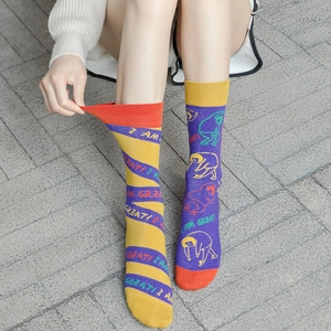 Detail of asymmetric mismatch socks with I AM GREAT text on outdoor grey stone floor