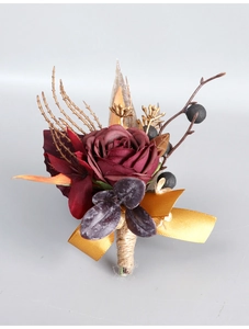 Nahaufnahme eines Vintage-Hochzeitsansteckers mit dunkelroter Rose und Golddekor
