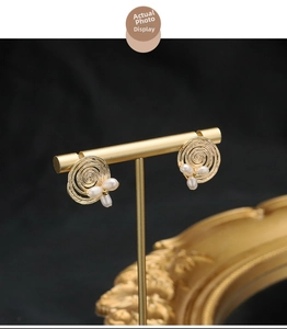 Macro detail of vintage 18k gold-plated earrings with spiral design and natural pearls