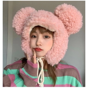 Detailed view of pink faux lamb wool hat with bear ears and white chin straps on a model
