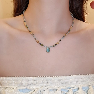 Detail of colorful beaded necklace with oval teal gemstone pendant on neck