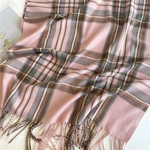 Dettaglio della trama del tessuto a quadri rosa e grigio e delle nappe della sciarpa