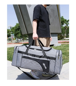 Outdoor street view of a large grey foldable oxford fabric travel bag held by a model