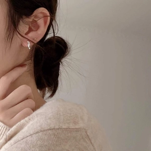 Close-up of silver S925 sterling silver knot stud earrings worn by a model